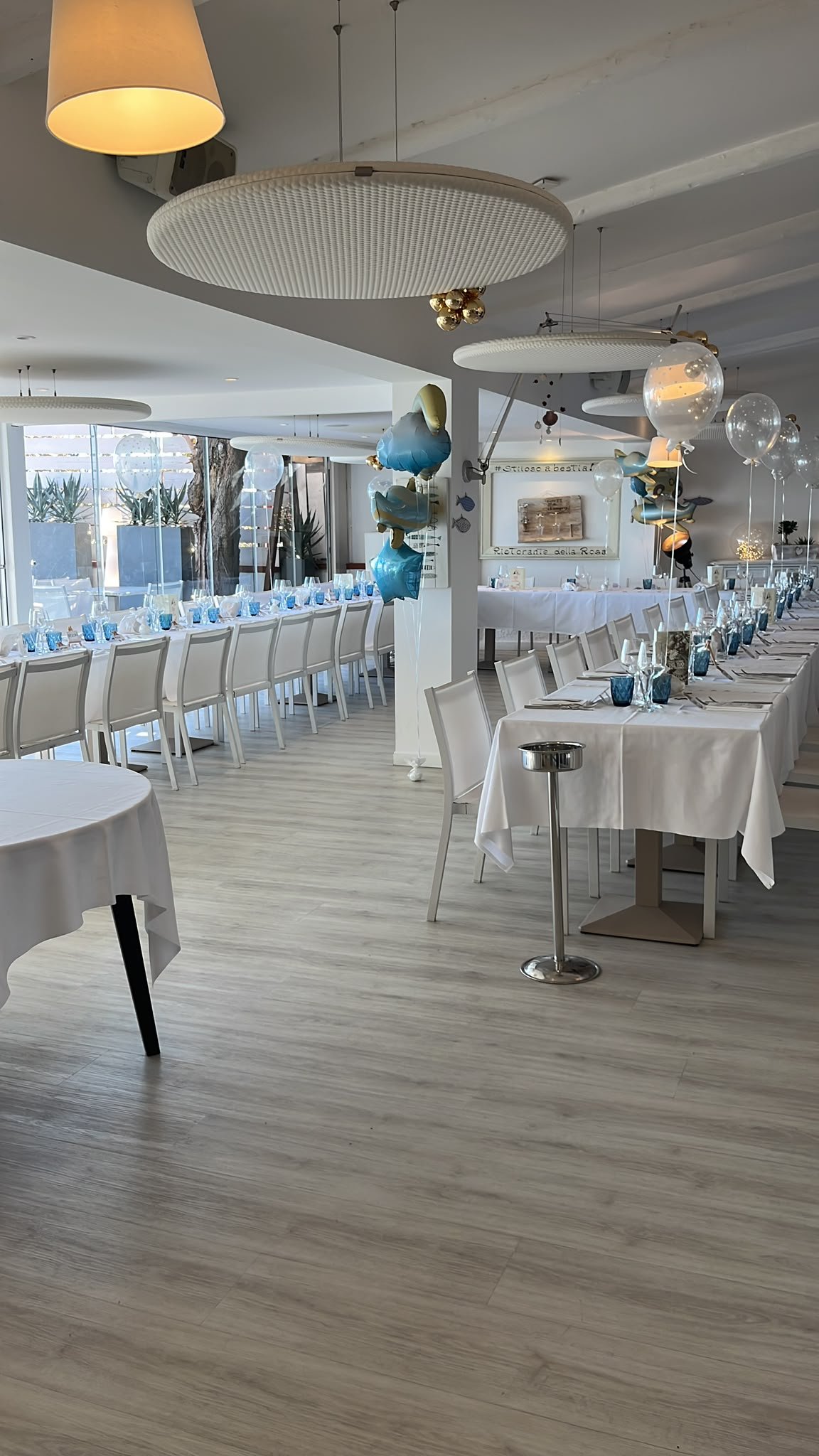 Sala del Ristorante della Rosa con lunghe tavolate bianche, bicchieri azzurri e palloncini per una festa